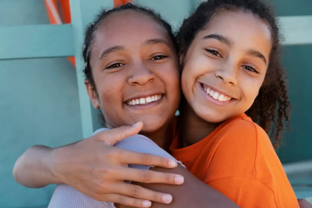 Two young girls looking happy and hugging each other